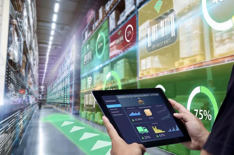 En person som styr ett digitalt logistiksystem via en surfplatta i ett lager.