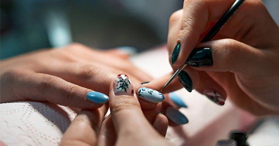 Närbild på en manikyr där nagelkonst målas under en nagelutbildning.