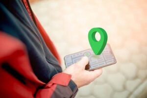 Person håller en smartphone med karta och grön platsmarkör