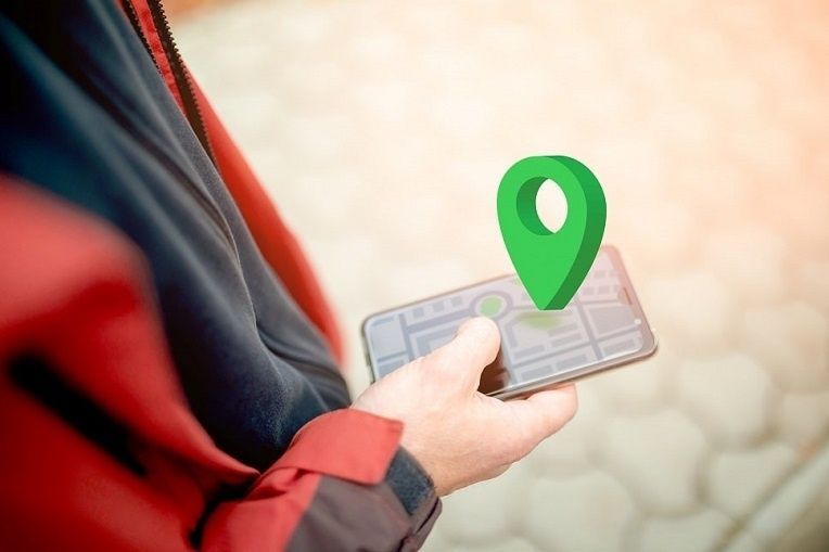 Person håller en smartphone med karta och grön platsmarkör