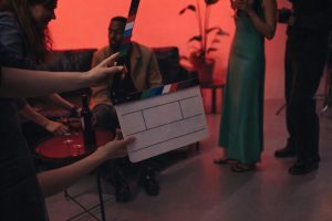 Händer som håller en filmklappa framför skådespelare på en filminspelning.